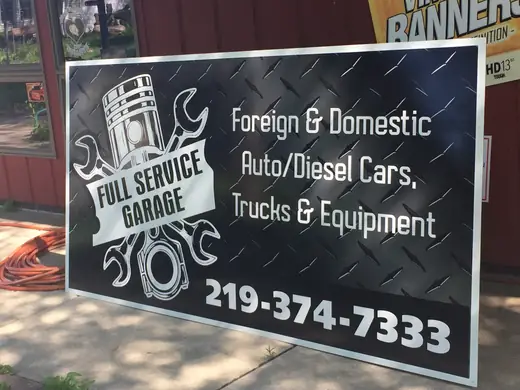 Black auto repair sign with white lettering and a phone number