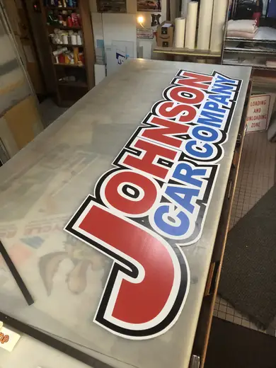 Large vinyl banner with red and blue lettering laid out on a production table