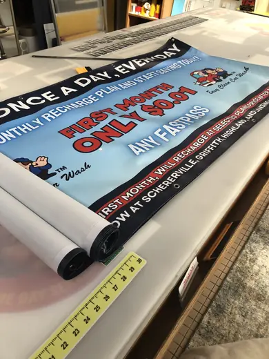 Printed promotional vinyl banner partly rolled on a work table