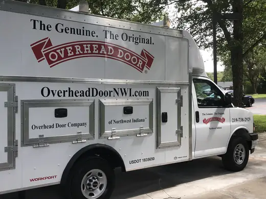 White work pickup with door lettering and a logo